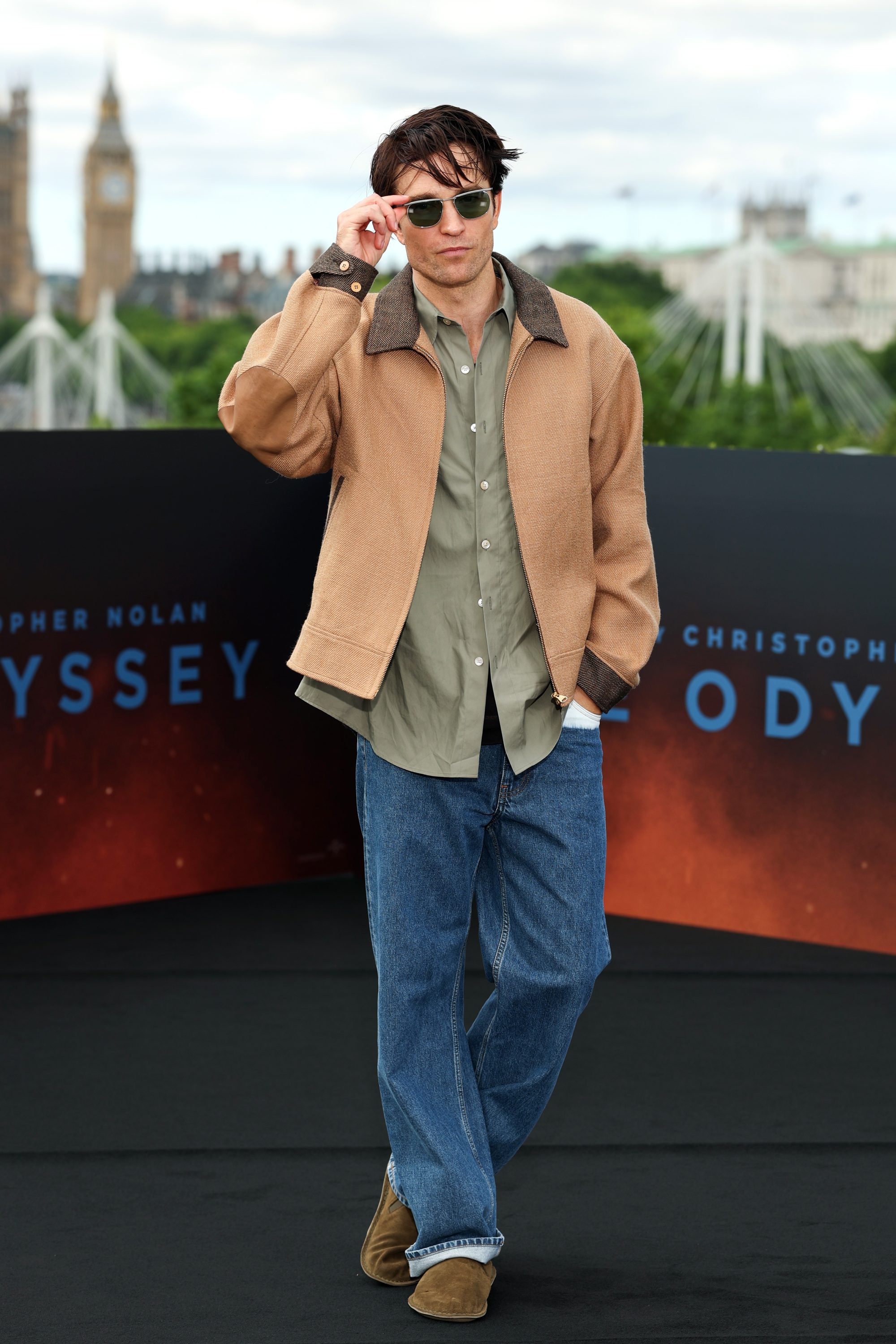 A man in a tan work jacket and jeans standing for a photo.