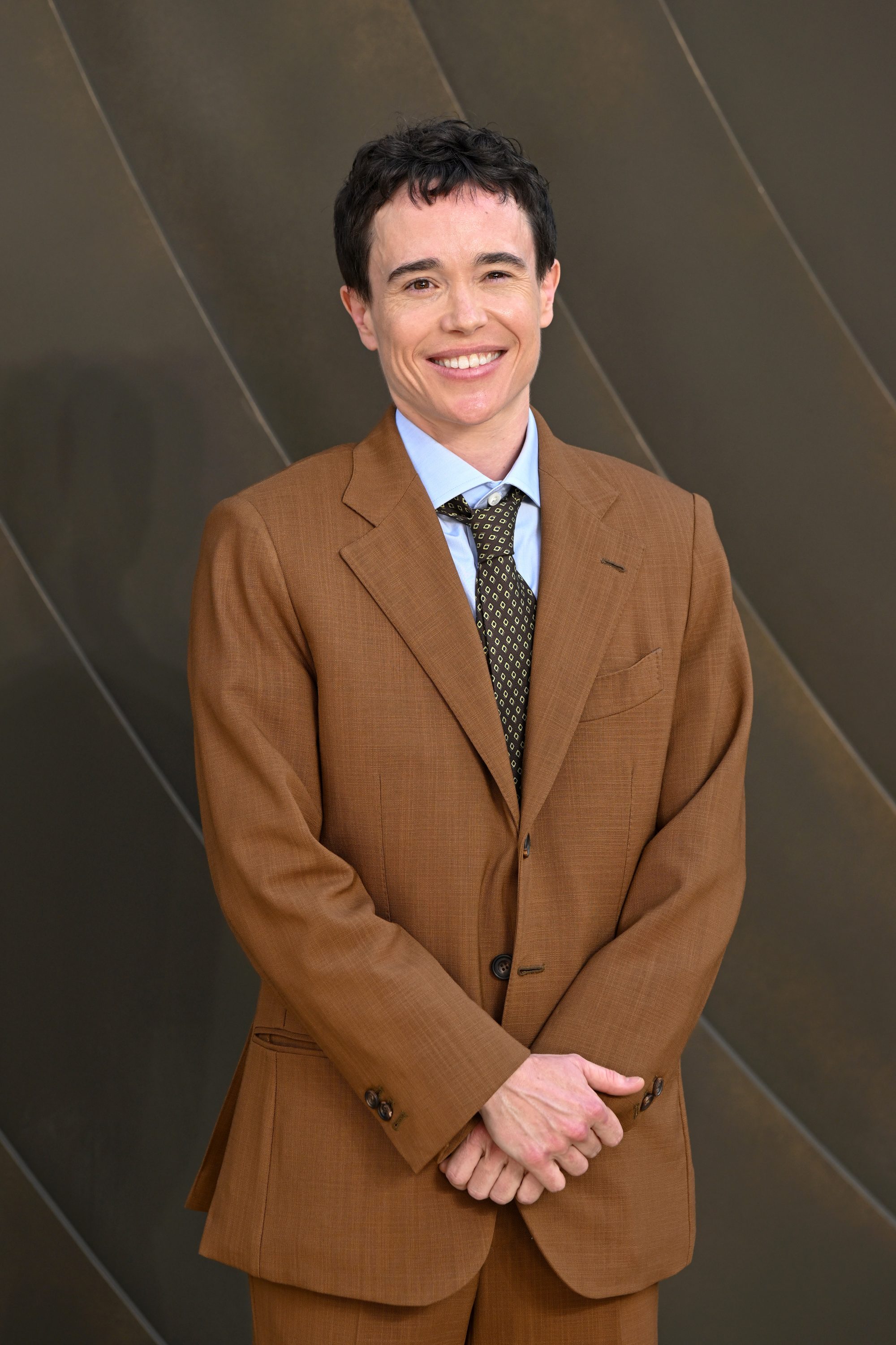 A man in a light brown suit standing for a photo.