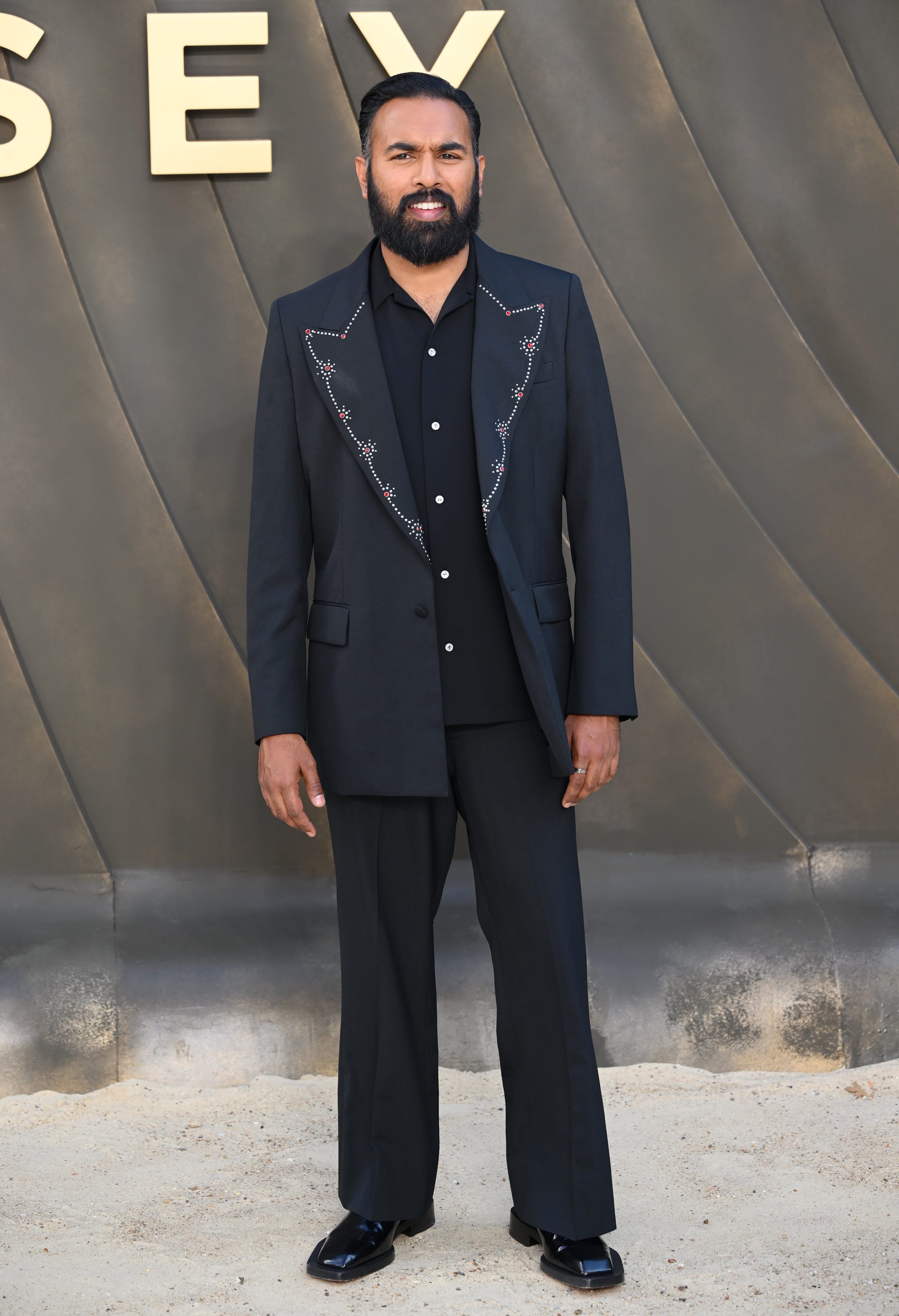 A man in a navy suit standing for a photo.