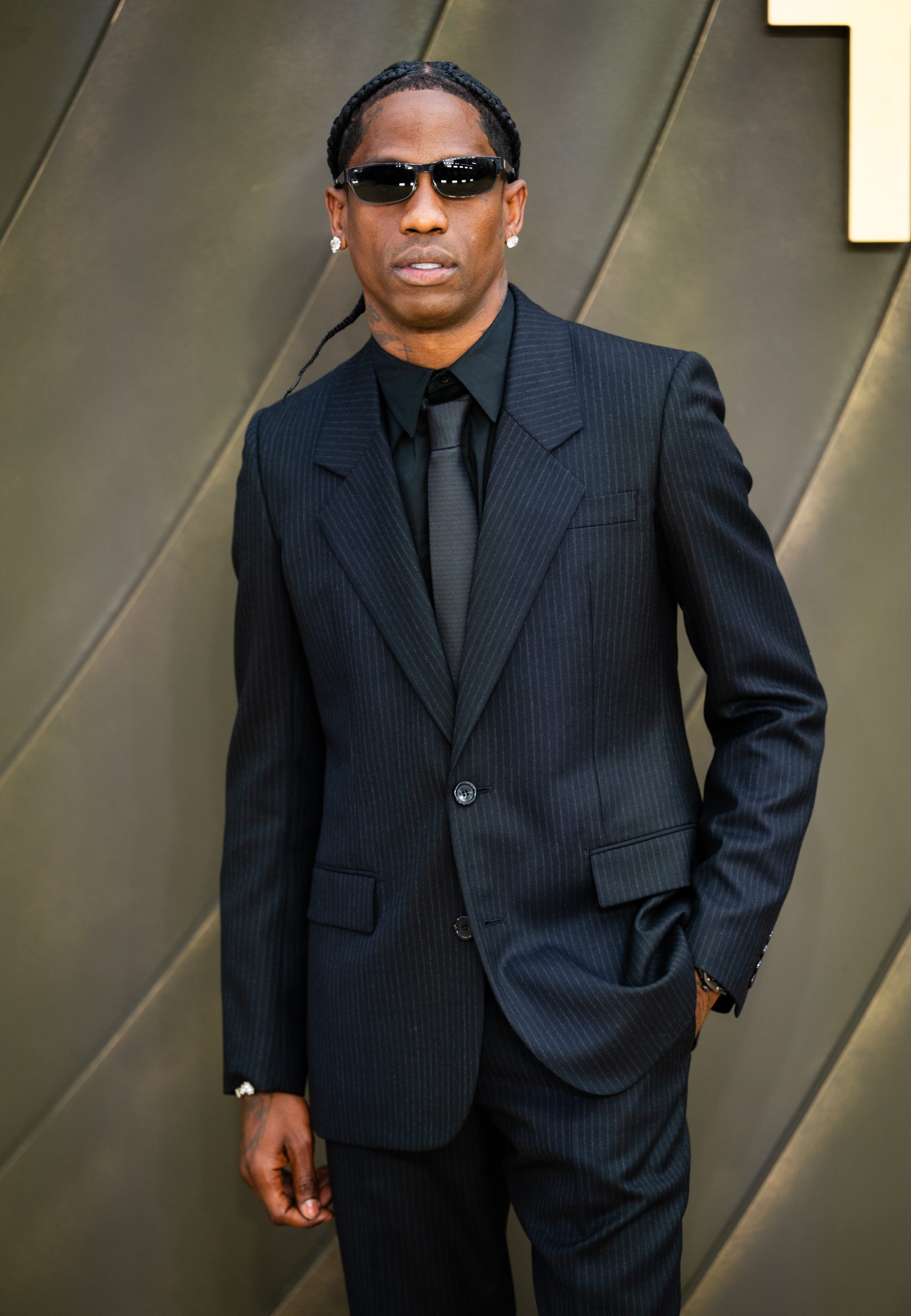 A man in a black suit and sunglasses standing for a photo.