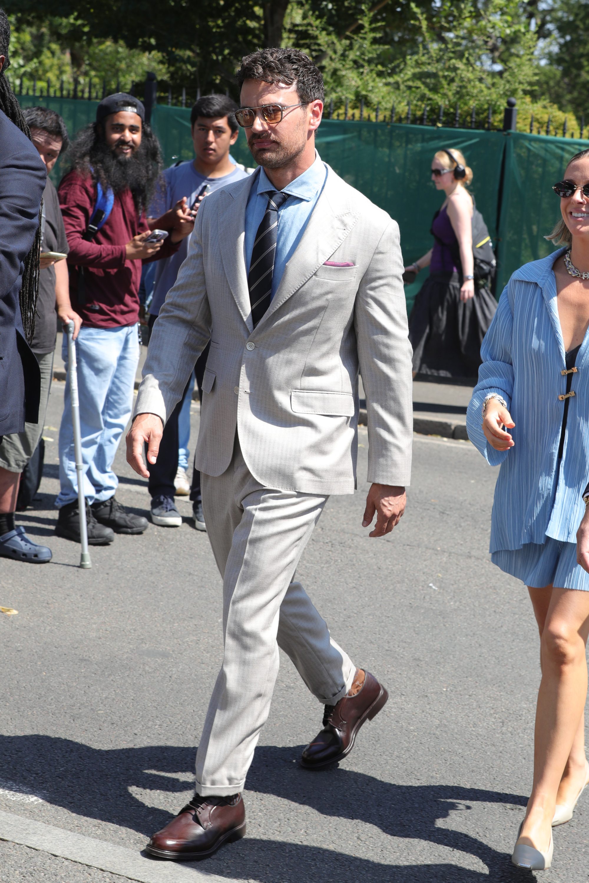 A photo of actor Theo James in a light grey suit and blue shirt