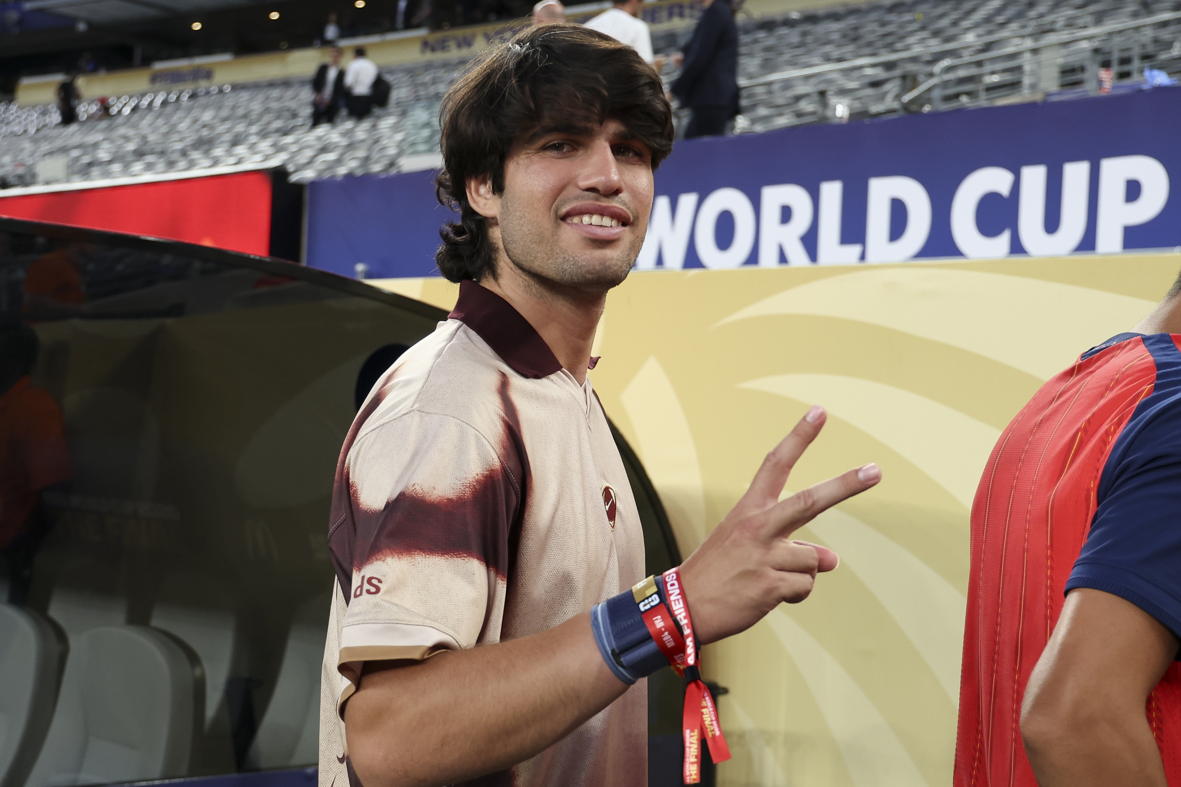 a man with floppy brown hair giving the peace sign to a photographer
