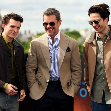 Actors Tom Holland, Matt Damon and Robert Pattinson standing in a line and smiling for a photo
