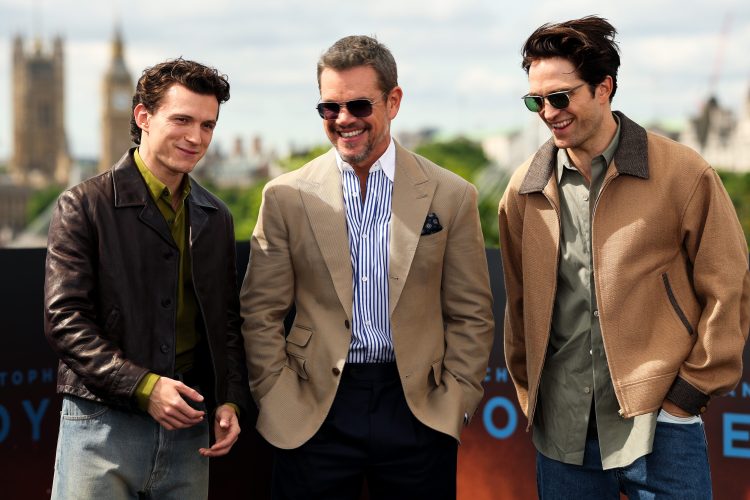 Actors Tom Holland, Matt Damon and Robert Pattinson standing in a line and smiling for a photo