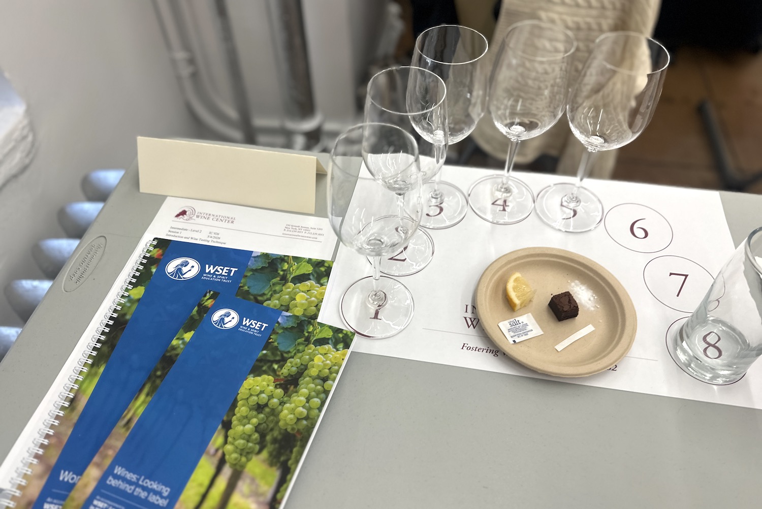the setup in a wset 2 classroom with books, empty wine glasses and a plate of salt and lemon