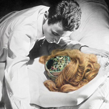 A black and white image of a man leaning over a woman on a bed, but the woman has a robotic head that is in full color