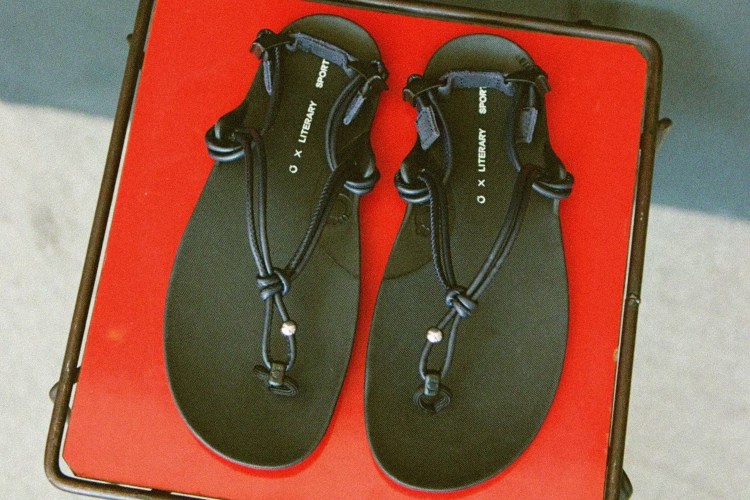 A pair of black roped sandals on a red tray
