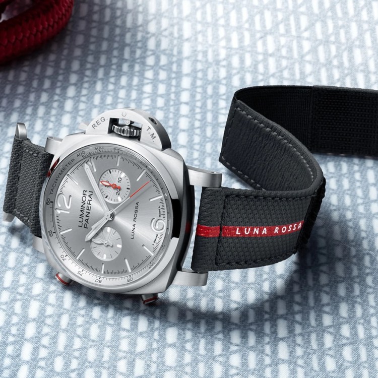 a silver watch with a black and red strap on a table