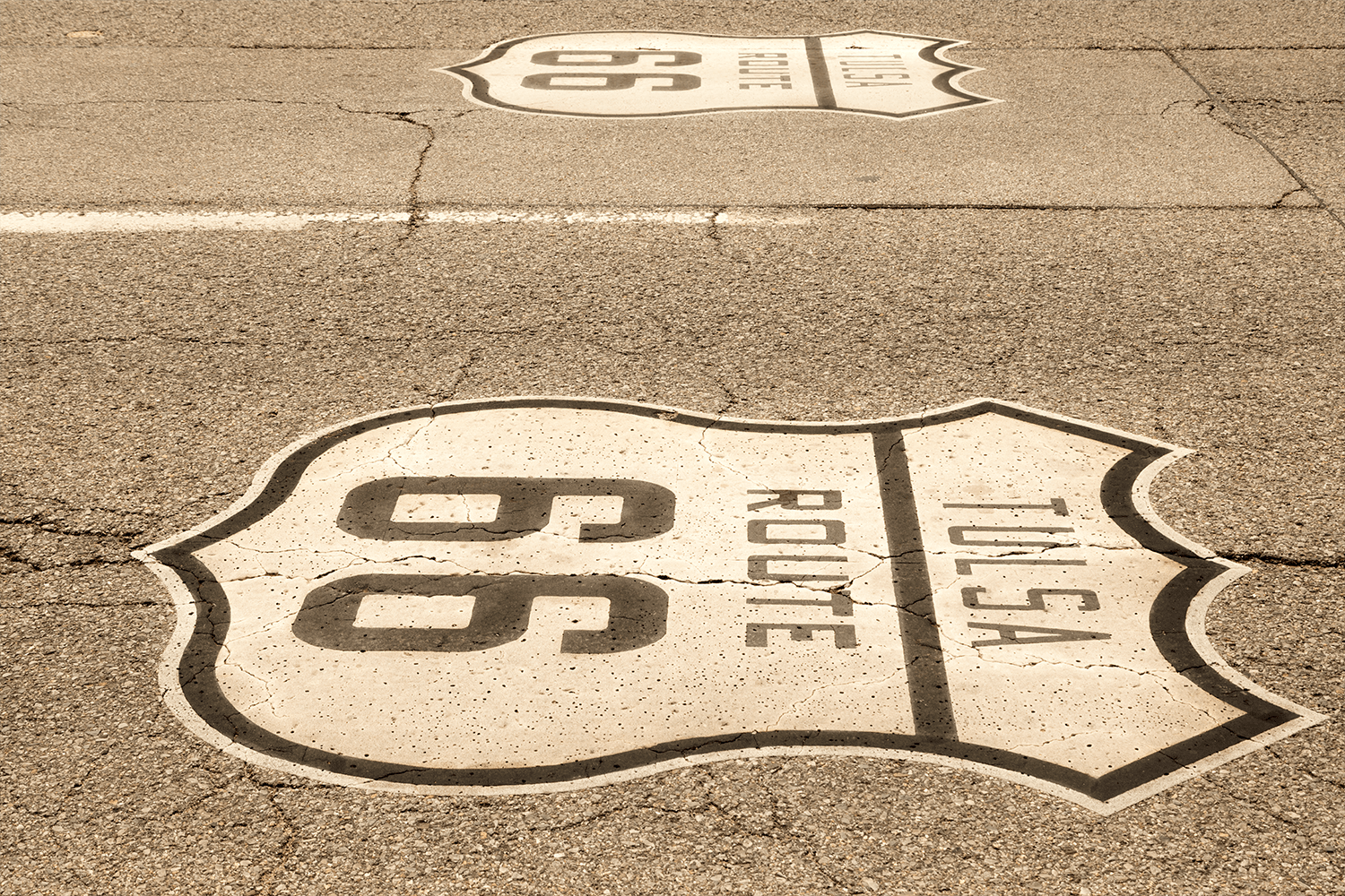 A brown and white road sign of the historic Route 66 on asphalt.