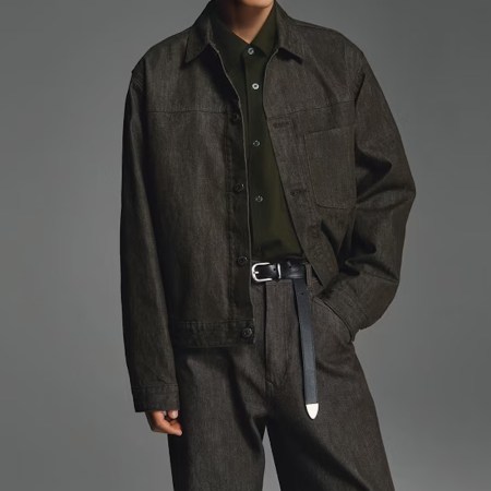 A model in a dark wash Uniqlo denim trucker jacket and jeans set against a grey background
