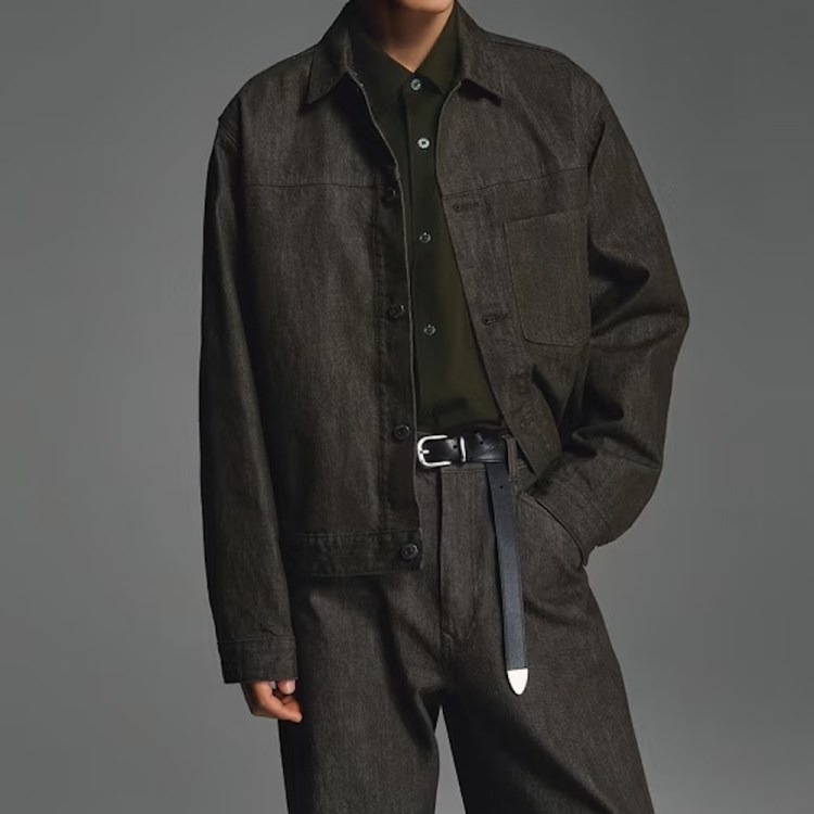 A model in a dark wash Uniqlo denim trucker jacket and jeans set against a grey background