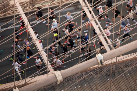 A group of runners cross the Brooklyn Bridge.