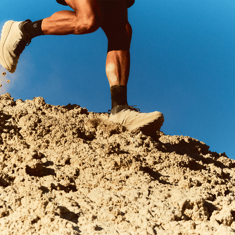 Man running on sandy dune in beige running shoes.