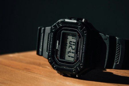 A black sport watch on a wooden table.