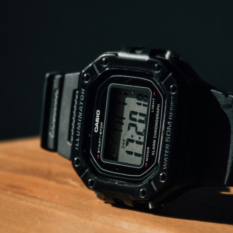 A black sport watch on a wooden table.