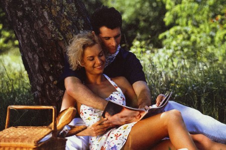 a 90s man and woman in embrace under a tree having a picnic