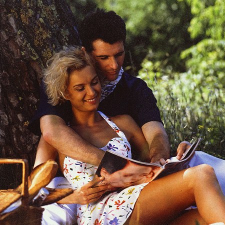 a 90s man and woman in embrace under a tree having a picnic