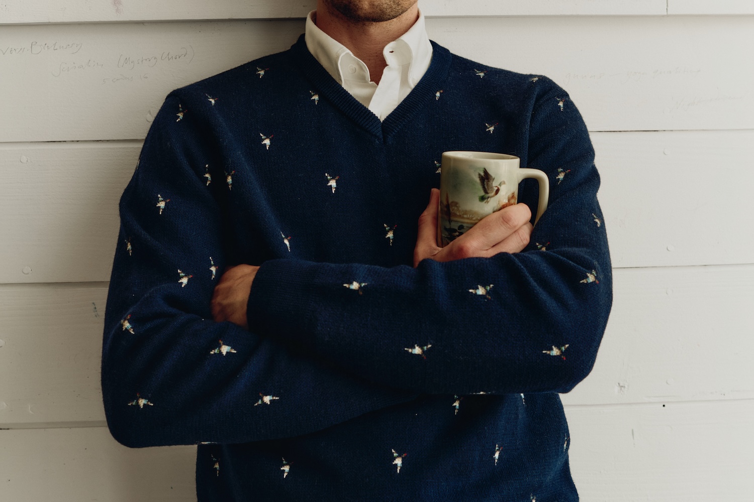 a model in a white button down under a navy embroidered sweater