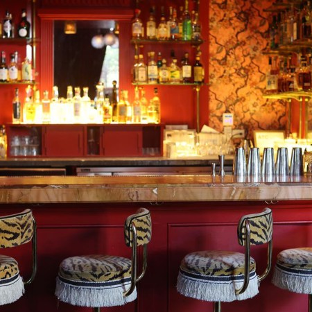 a red bar with four animal print fringed stools in front of it