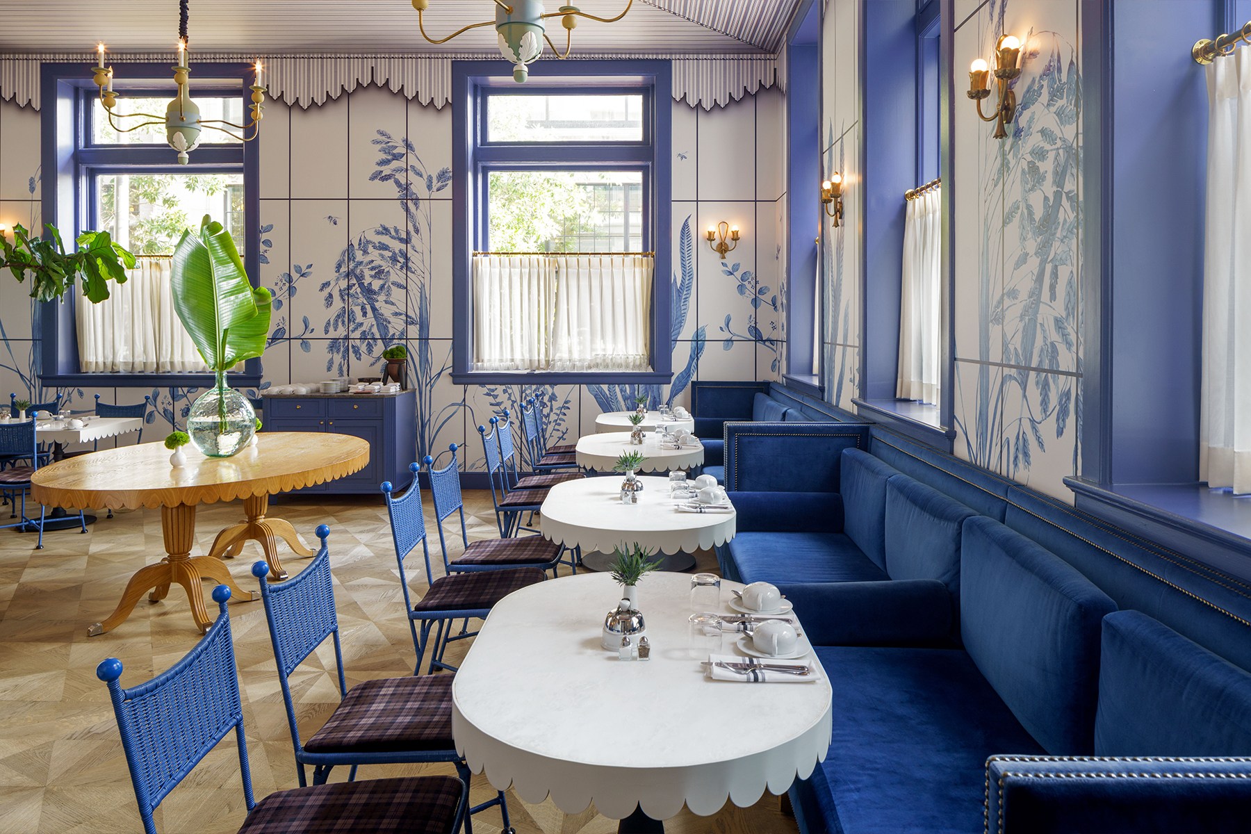 a breakfast room with white and blue walls, white tables, and blue velvet seating