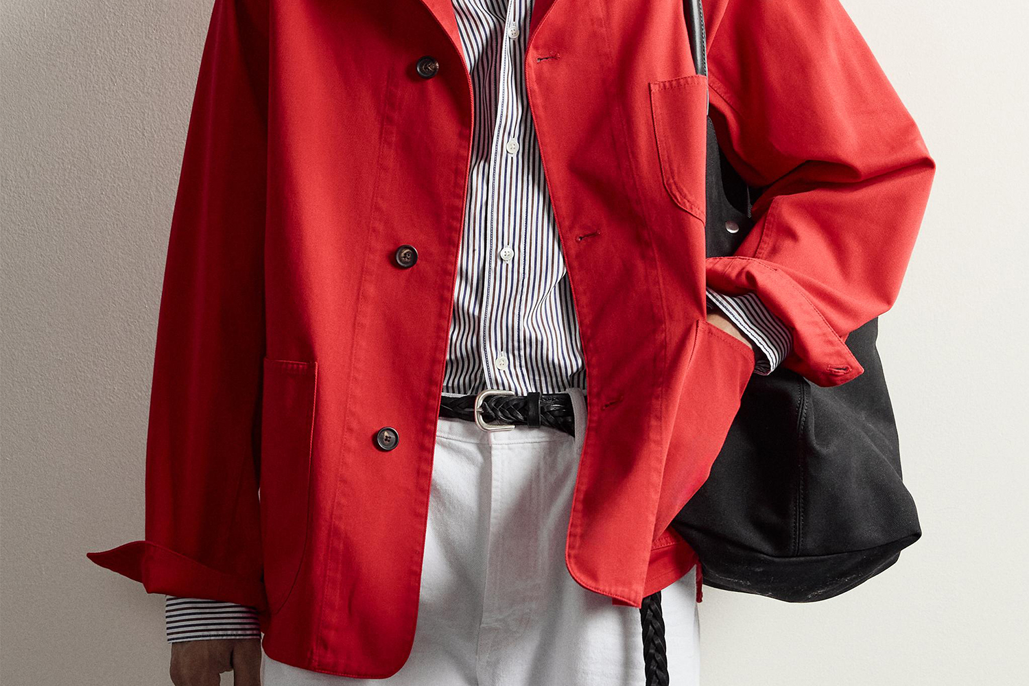 a model in a red coat, striped shirt and white pants