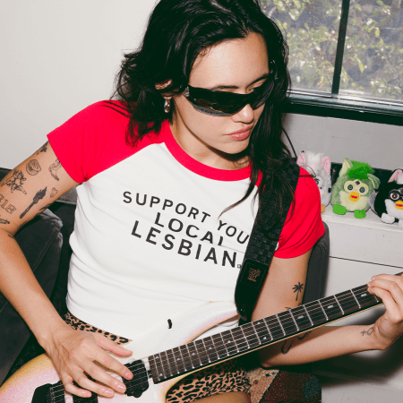 rivkah reyes wearing sunglasses playing a guitar with furbies in the background