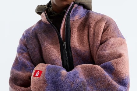 Person wearing a pink and purple tie-dye fleece jacket with a black zipper and a red North Face patch on the sleeve.