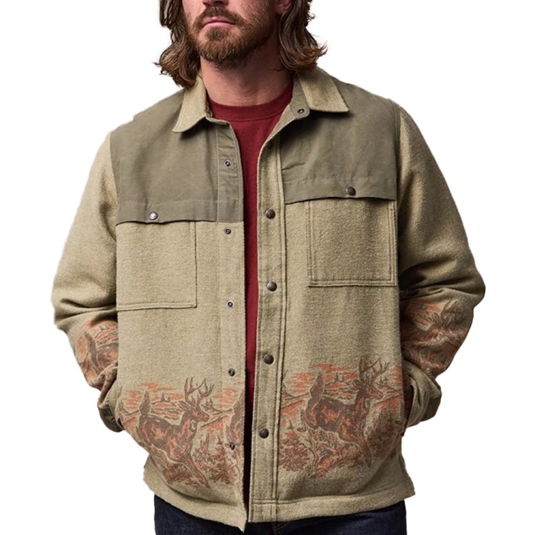 Man in a beige and olive green jacket with a deer and forest pattern along the bottom and sleeves.